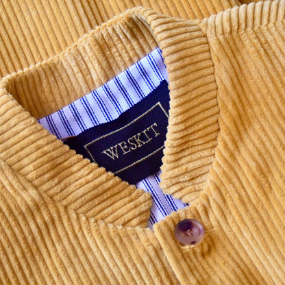 Slim Cut Nehru Gilet in Ochre Coloured Pure Cotton Corduroy. The perfect alternative to a jacket, this gilet will keep you warm and smart in winter. Cut, Made and Finished by Hand in London.  Collar Detail showing Nehru collar, Cornu buttons and black and gold embroidered label.