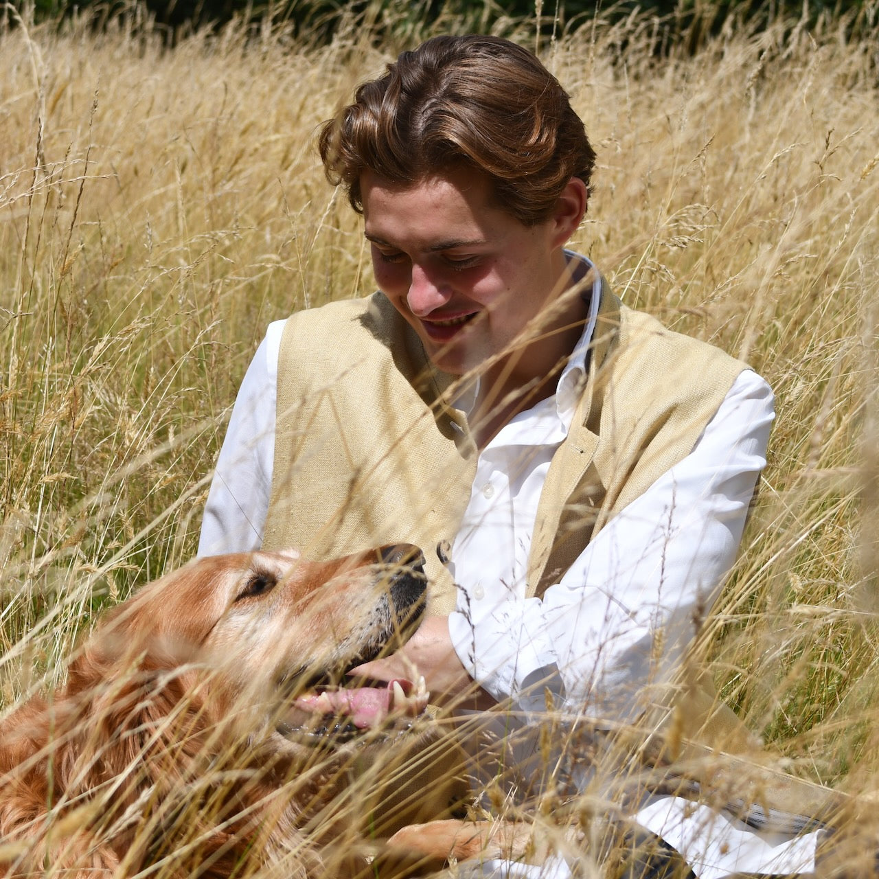 Lighter weight fitted gilet in sandy straw coloured silk weave fabric. Handmade in London this Nehru style gilet boast a Nehru collar, five pockets and is fully lined in pure cotton ticking. Seated shot with dog.