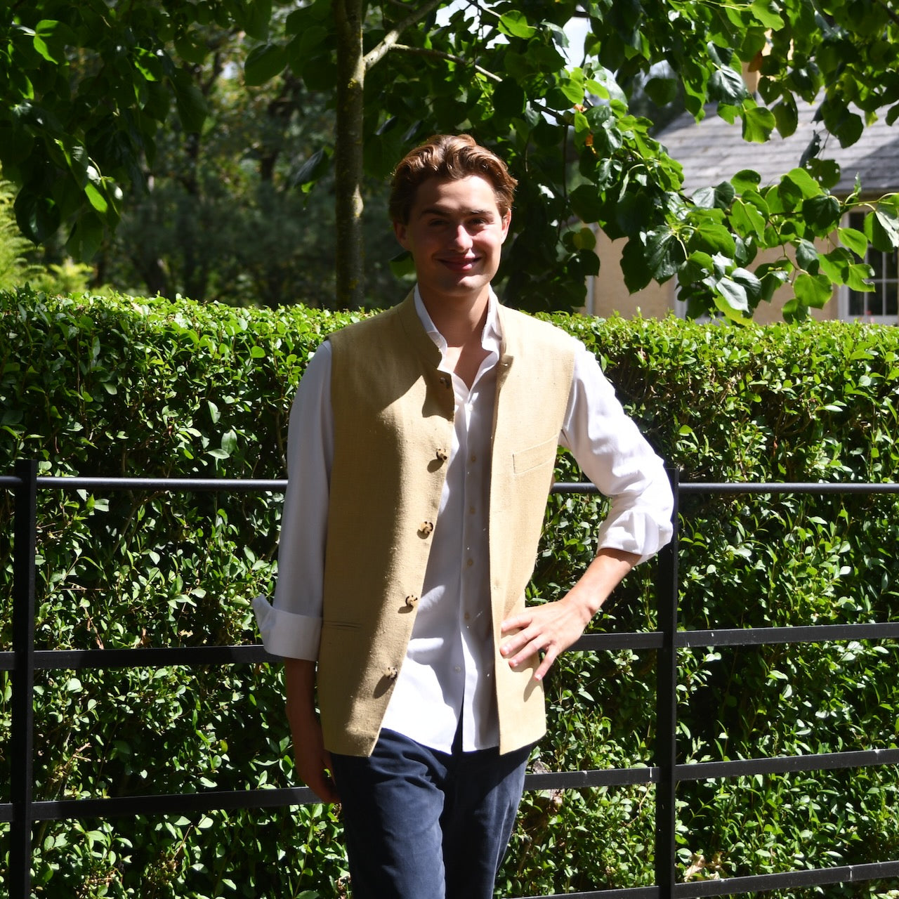 Sand Coloured Silk Matka Gilet. Handmade in London. Photographed in Wales. Shown against Estate Fencing with luscious green backdrop.