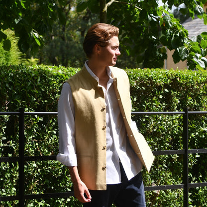Sand Coloured Silk Matka Gilet. Handmade in London. Photographed in Wales. Shown against Estate Fencing with luscious green backdrop. Side View.