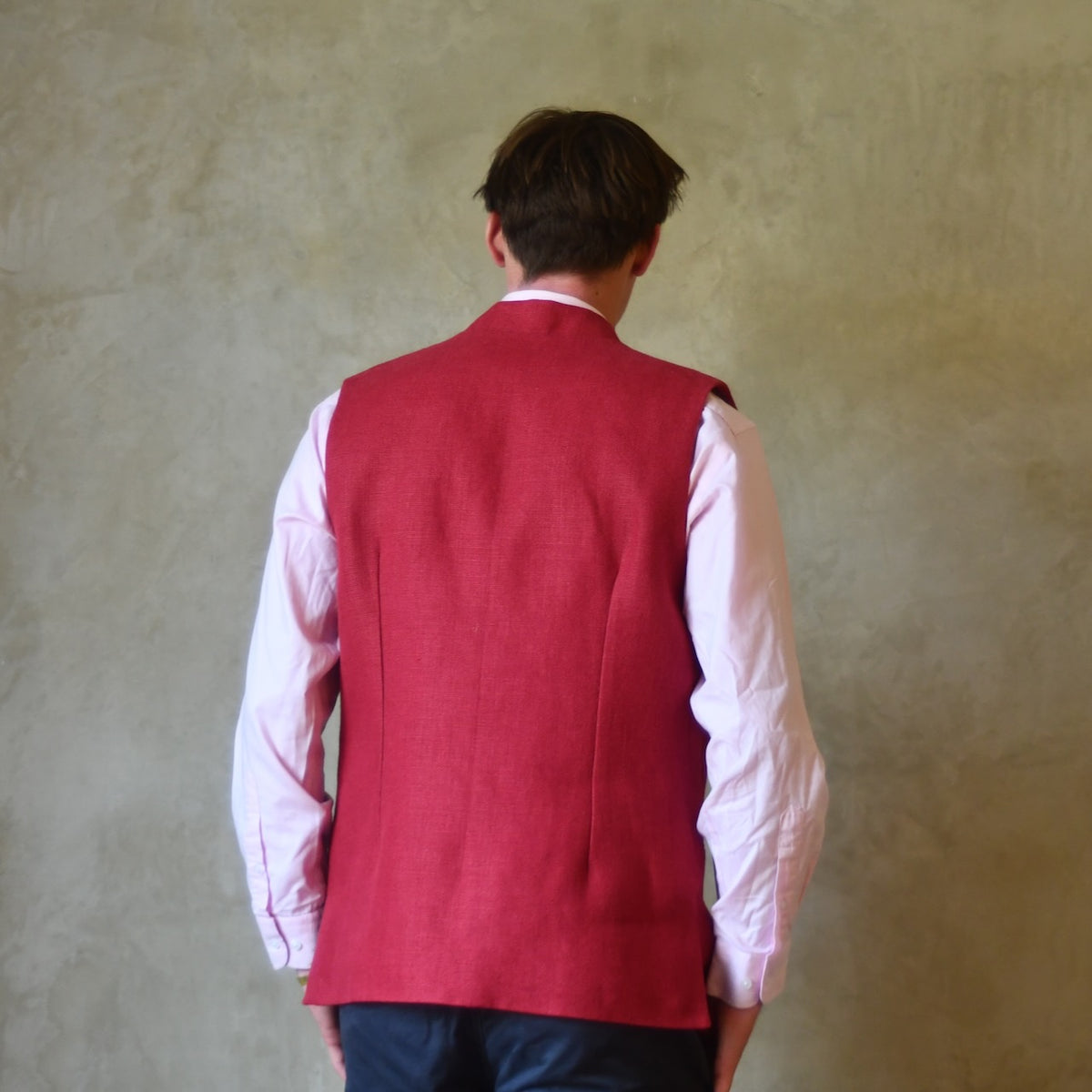 Rear view of Red Linen Nehru-Style Fitted Waistcoat. Handmade in London. Bespoke and ready to ship. Shown buttoned over a pink shirt.