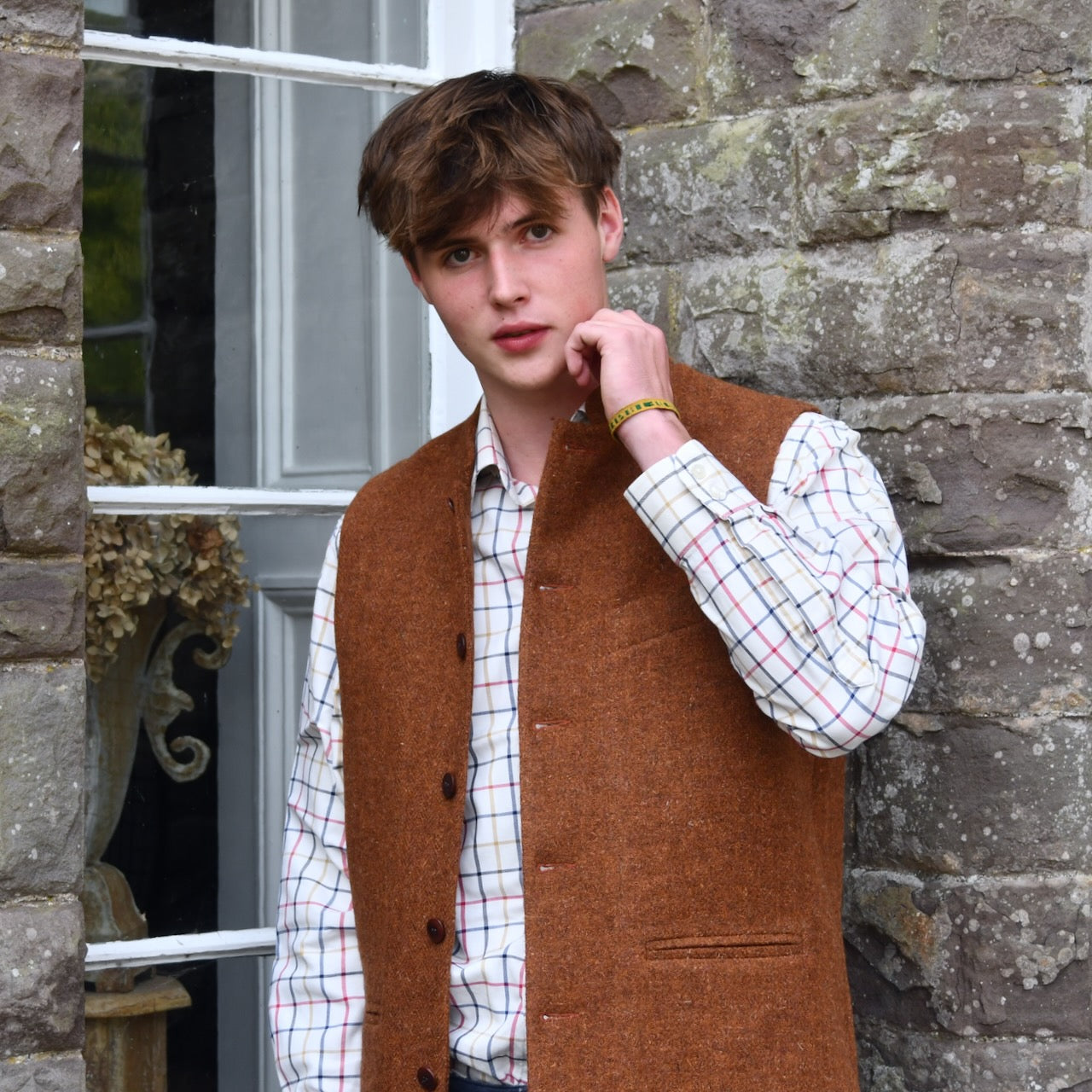 Bespoke Waistcoat in pure wool tweed in russet brown. Handmade in London, this Nehru-style gilet is shown worn open over a checked shirt.