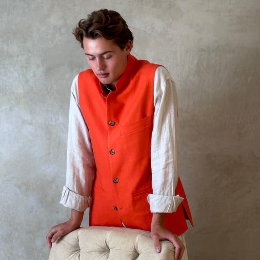 Slim fit nehru style gilet in summer weight silk weave fabric. Handmade in London, this orange silk matka fitted waistcoat has a Nehru collar, Courtney & Co buttons and is fully lined in striped cotton ticking. Standing Shot.