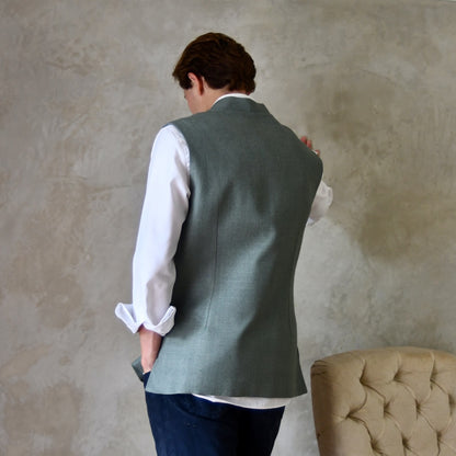 Rear view of Slim cut summer weight nehru style gilet in pale green silk weave. Handmade in London this fitted waistcoat has a Nehru  collar and is fully lined in cotton ticking. Real horn buttons. Rear Shot.