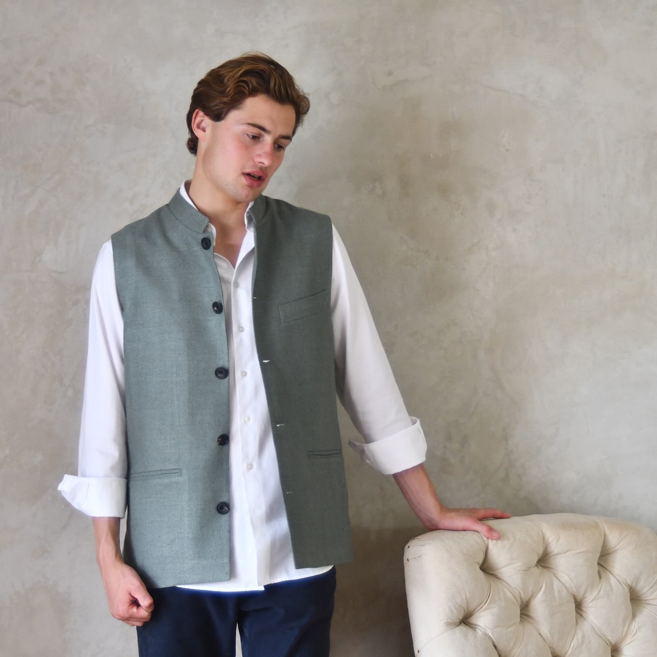 Slim cut summer weight nehru style gilet in pale green silk weave. Handmade in London this fitted waistcoat has a Nehru  collar and is fully lined in cotton ticking. Real horn buttons. Standing view.