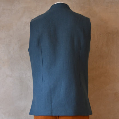 Light blue loose cut linen gilet from Weskit. Handmade in London, this slubby linen waistcoat is made in pure Irish linen and lined in striped cotton ticking. Mandarin collar and Courtney and Co buttons. Entirely made in Great Britain. Back View shot.