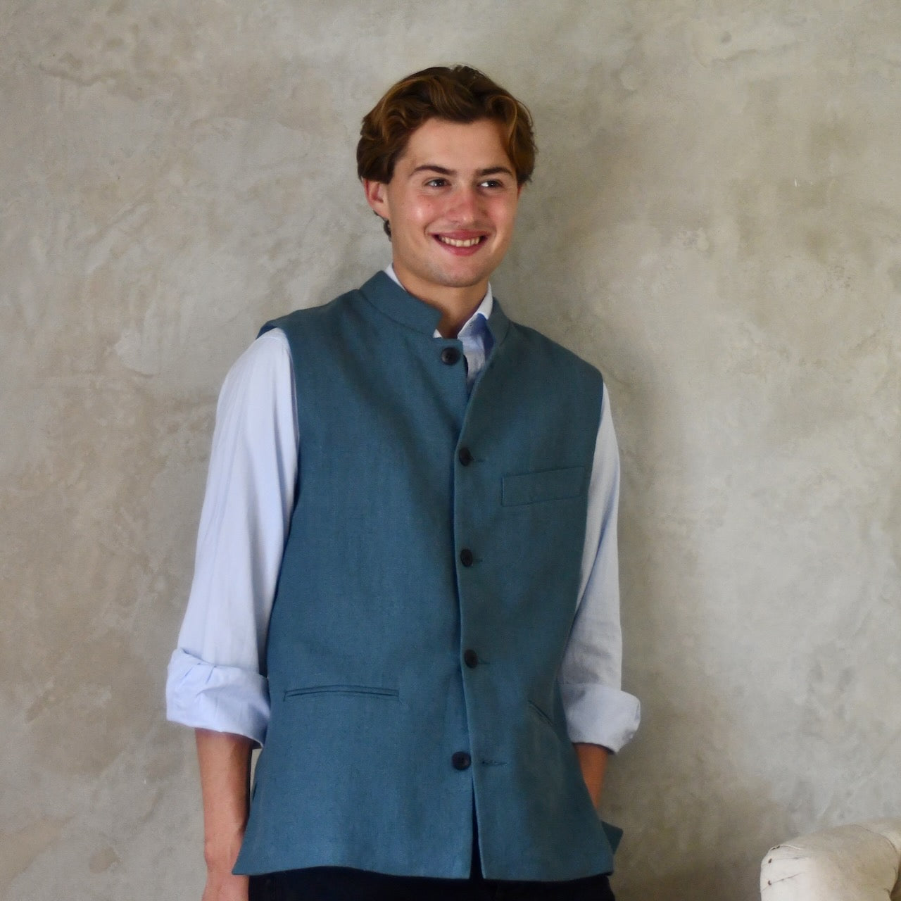 Light blue Slim cut linen gilet from Weskit. Handmade in London, this slubby linen waistcoat is made in pure Irish linen and lined in striped cotton ticking. Mandarin collar and Courtney and Co buttons. Entirely made in Great Britain. Buttoned Front View.