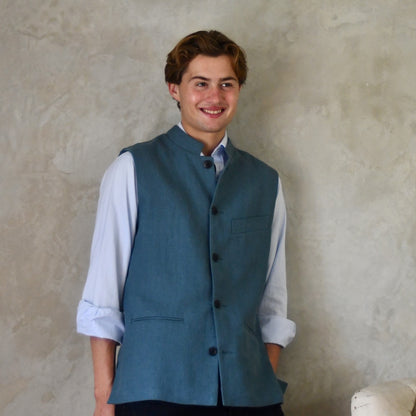 Light blue Slim cut linen gilet from Weskit. Handmade in London, this slubby linen waistcoat is made in pure Irish linen and lined in striped cotton ticking. Mandarin collar and Courtney and Co buttons. Entirely made in Great Britain. Buttoned Front View.