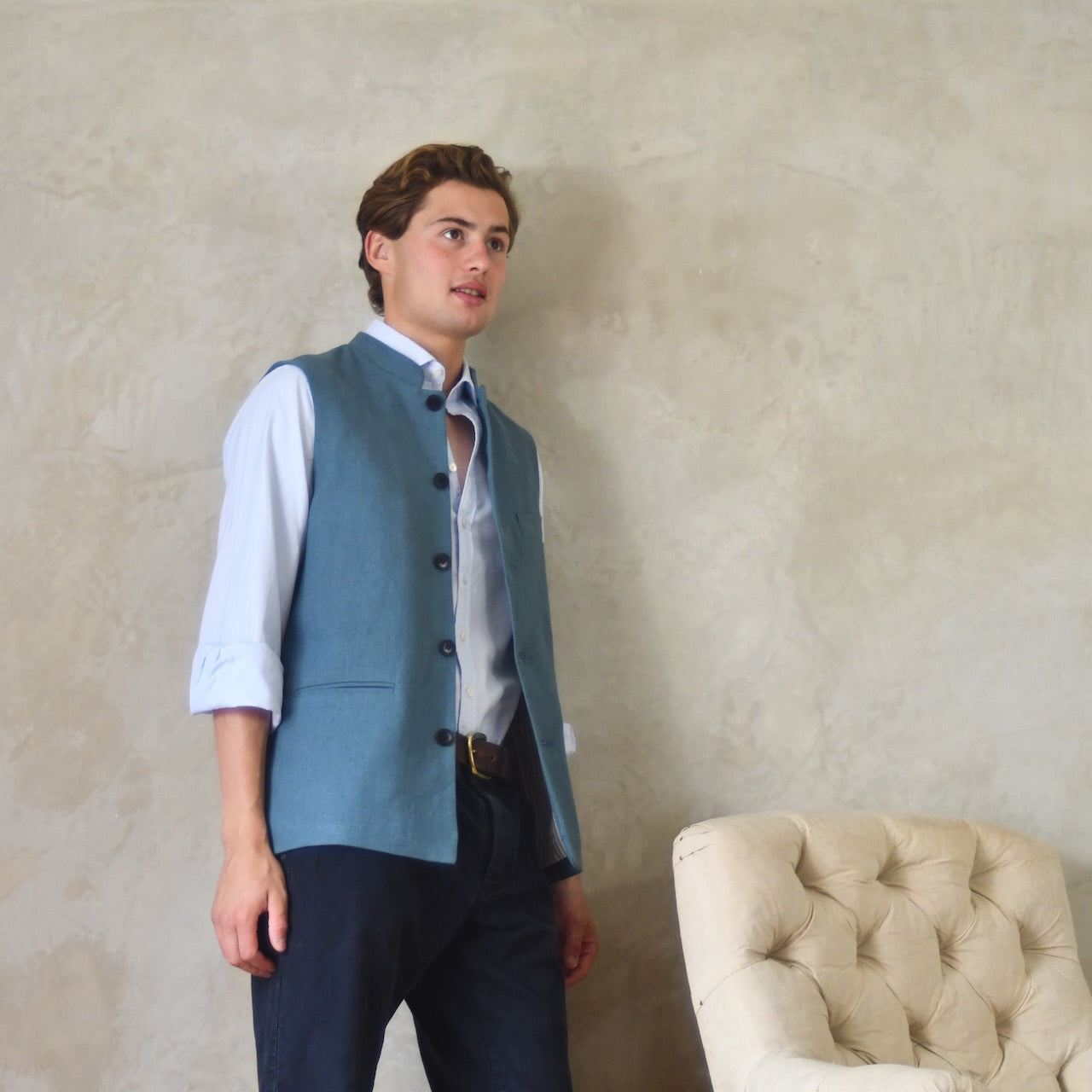 Light blue loose cut linen gilet from Weskit. Handmade in London, this slubby linen waistcoat is made in pure Irish linen and lined in striped cotton ticking. Mandarin collar and Courtney and Co buttons. Entirely made in Great Britain. Side View, Open.