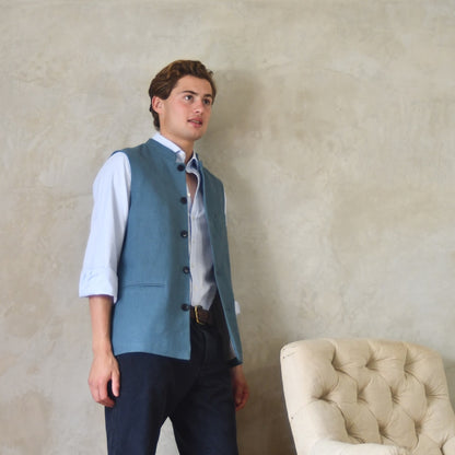 Light blue loose cut linen gilet from Weskit. Handmade in London, this slubby linen waistcoat is made in pure Irish linen and lined in striped cotton ticking. Mandarin collar and Courtney and Co buttons. Entirely made in Great Britain. Side View, Open.