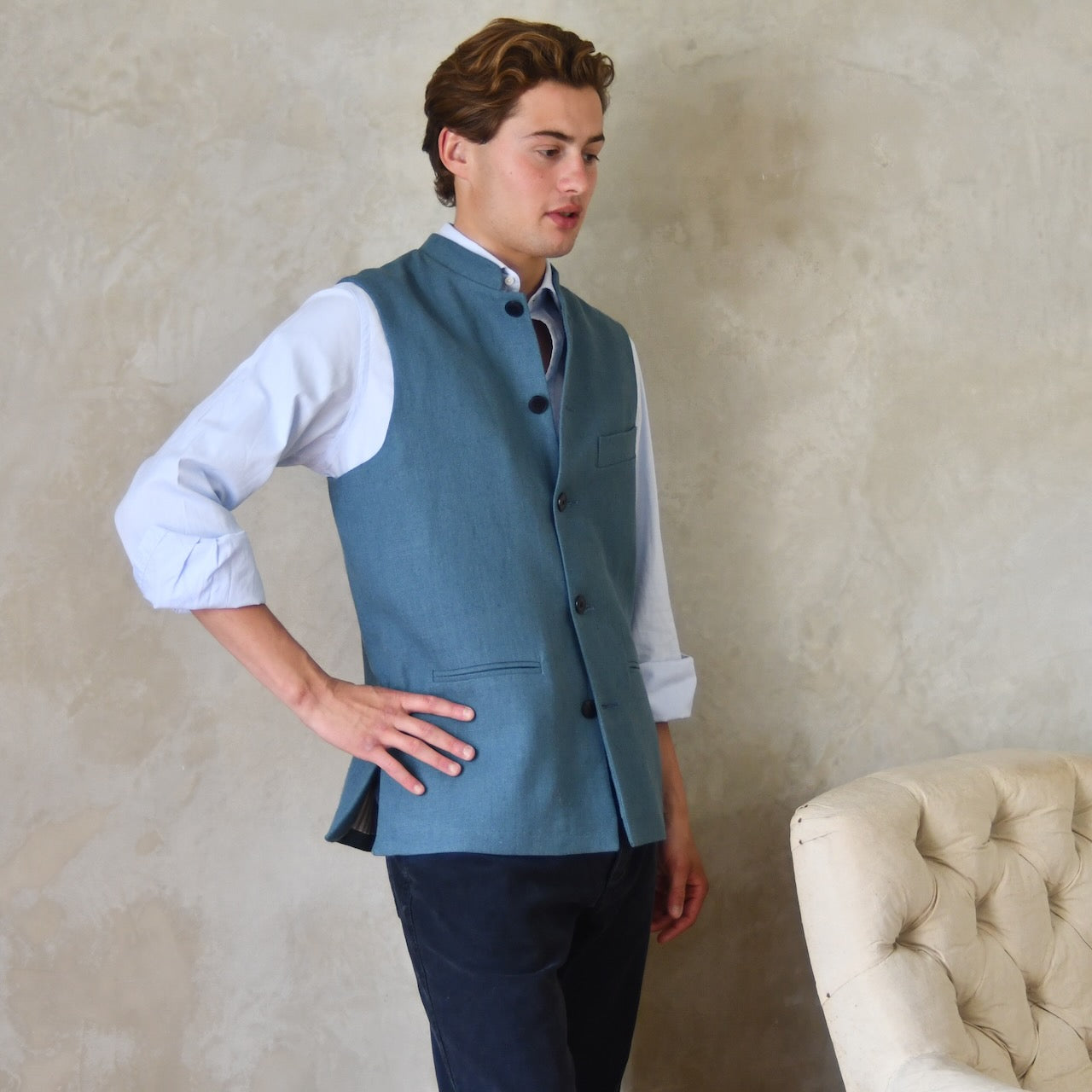 Light blue loose cut linen gilet from Weskit. Handmade in London, this slubby linen waistcoat is made in pure Irish linen and lined in striped cotton ticking. Mandarin collar and Courtney and Co buttons. Entirely made in Great Britain. Closed Side View.