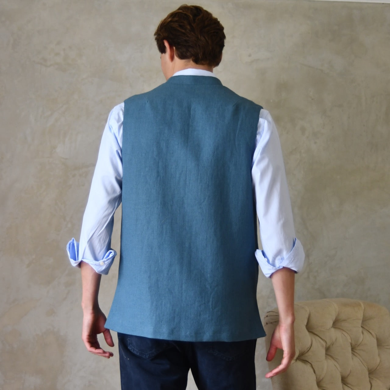 Light blue loose cut linen gilet from Weskit. Handmade in London, this slubby linen waistcoat is made in pure Irish linen and lined in striped cotton ticking. Mandarin collar and Courtney and Co buttons. Entirely made in Great Britain. Rear View.