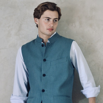 Light blue Slim Cut linen gilet from Weskit. Handmade in London, this slubby linen waistcoat is made in pure Irish linen and lined in striped cotton ticking. Mandarin collar and Courtney and Co buttons. Entirely made in Great Britain. Close Up shot.