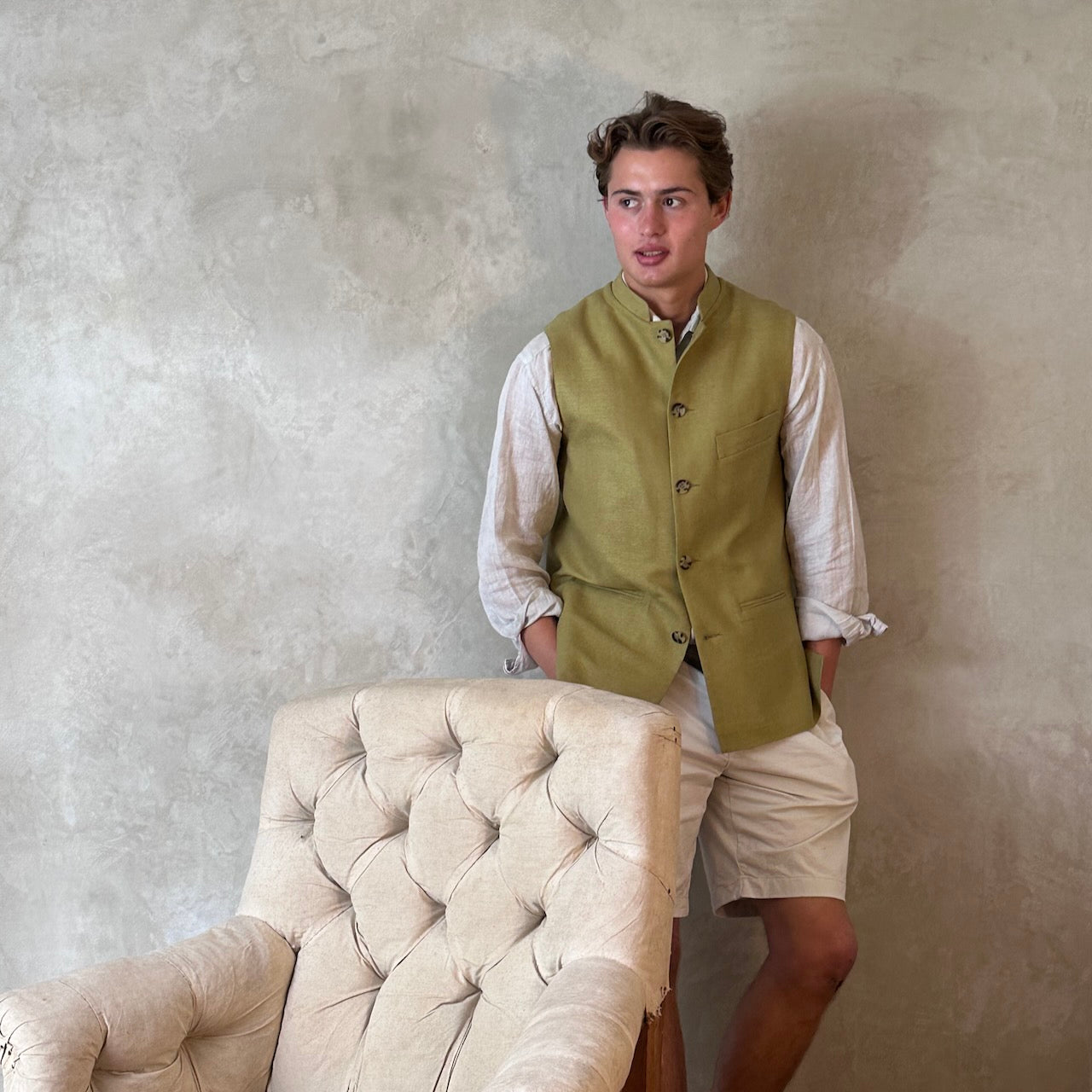 Relaxed fit summer weight gilet in green silk weave. Handmade in London this gilet has a Mandarin collar and is fully lined in pure cotton ticking. Made in Great Britain. Shown over white linen co-ordinates,