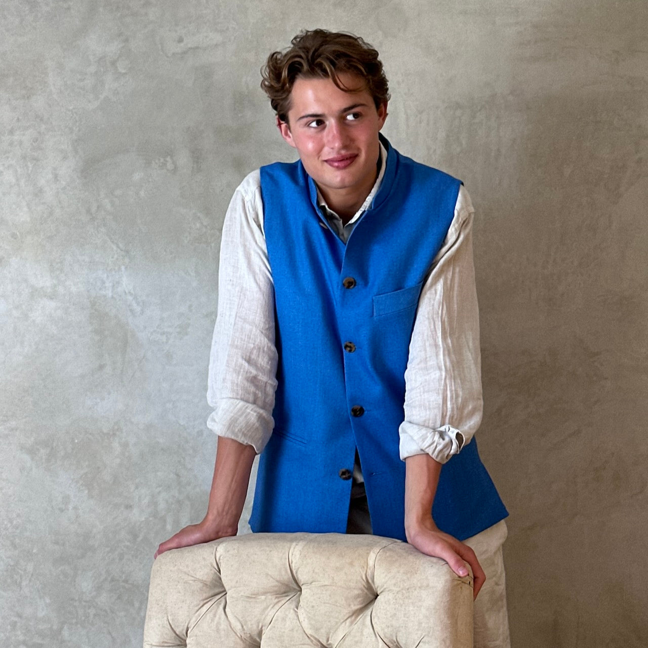 Slim fit gilet in sky blue summer weight silk weave. Handmade in London this fitted waistcoat has five pockets and a Nehru collar. Made in Great Britain. Modelled standing shot.
