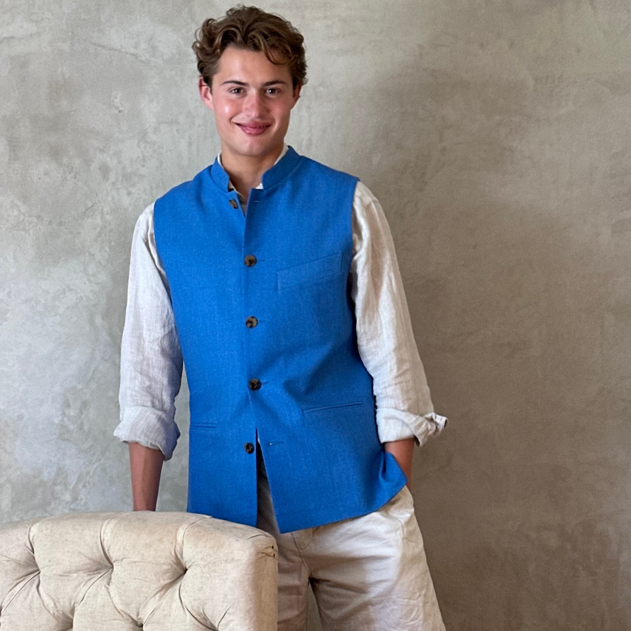 Slim fit gilet in sky blue summer weight silk weave. Handmade in London this fitted waistcoat has five pockets and a Nehru collar. Made in Great Britain. Standing front shot.