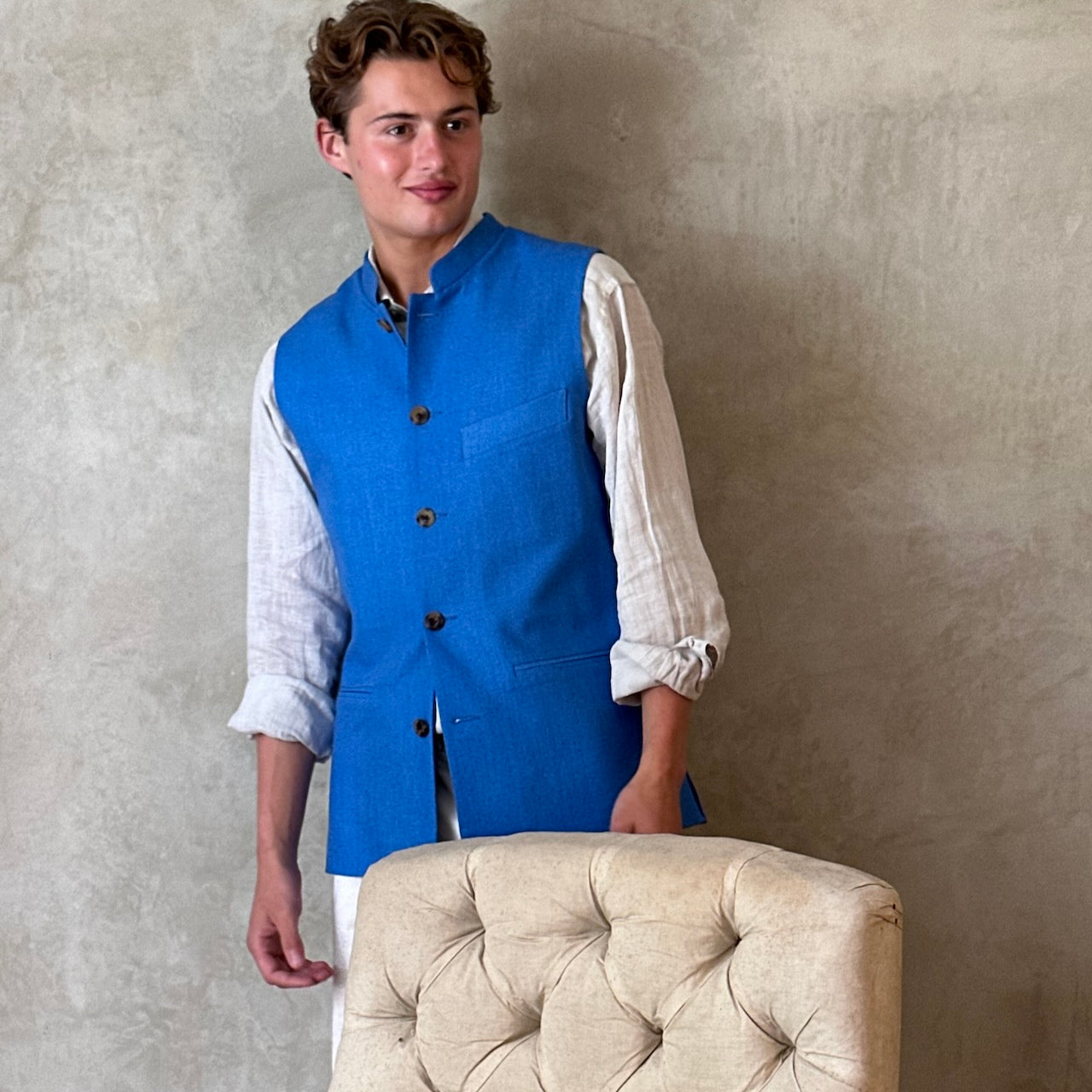 Slim fit gilet in sky blue summer weight silk weave. Handmade in London this fitted waistcoat has five pockets and a Nehru collar. Made in Great Britain. Standing shot.