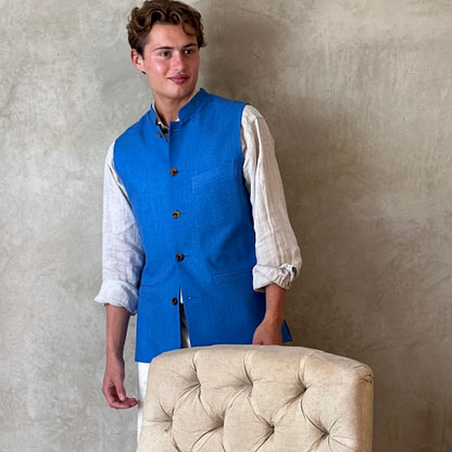 Slim fit gilet in sky blue summer weight silk weave. Handmade in London this fitted waistcoat has five pockets and a Nehru collar. Made in Great Britain. Standing shot.