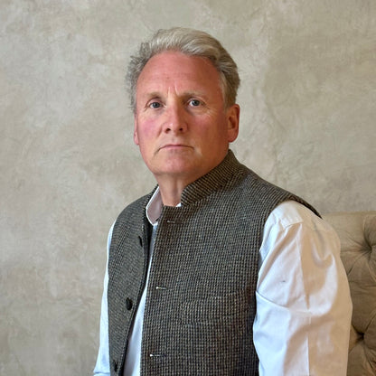 Warm Nehru Style Gilet in pure wool tweed from Hawick. Handmade in London this waistcoat has a gentle patterning in blue and shades of taupe and grey. Ample pocket space, side vents and a nead Mandarin Collar. Close Up shot.