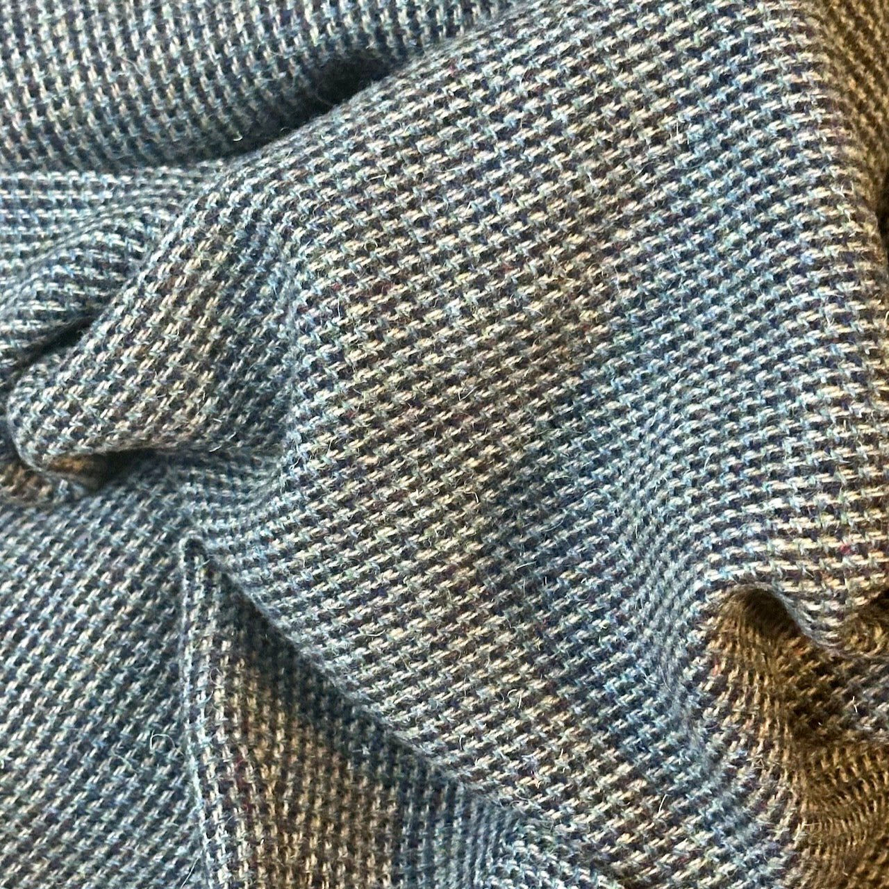 Fabric Close up of Warm Nehru Style Gilet in pure wool tweed from Hawick. Handmade in London this waistcoat has a gentle patterning in blue and shades of taupe and grey. Ample pocket space, side vents and a nead Mandarin Collar.
