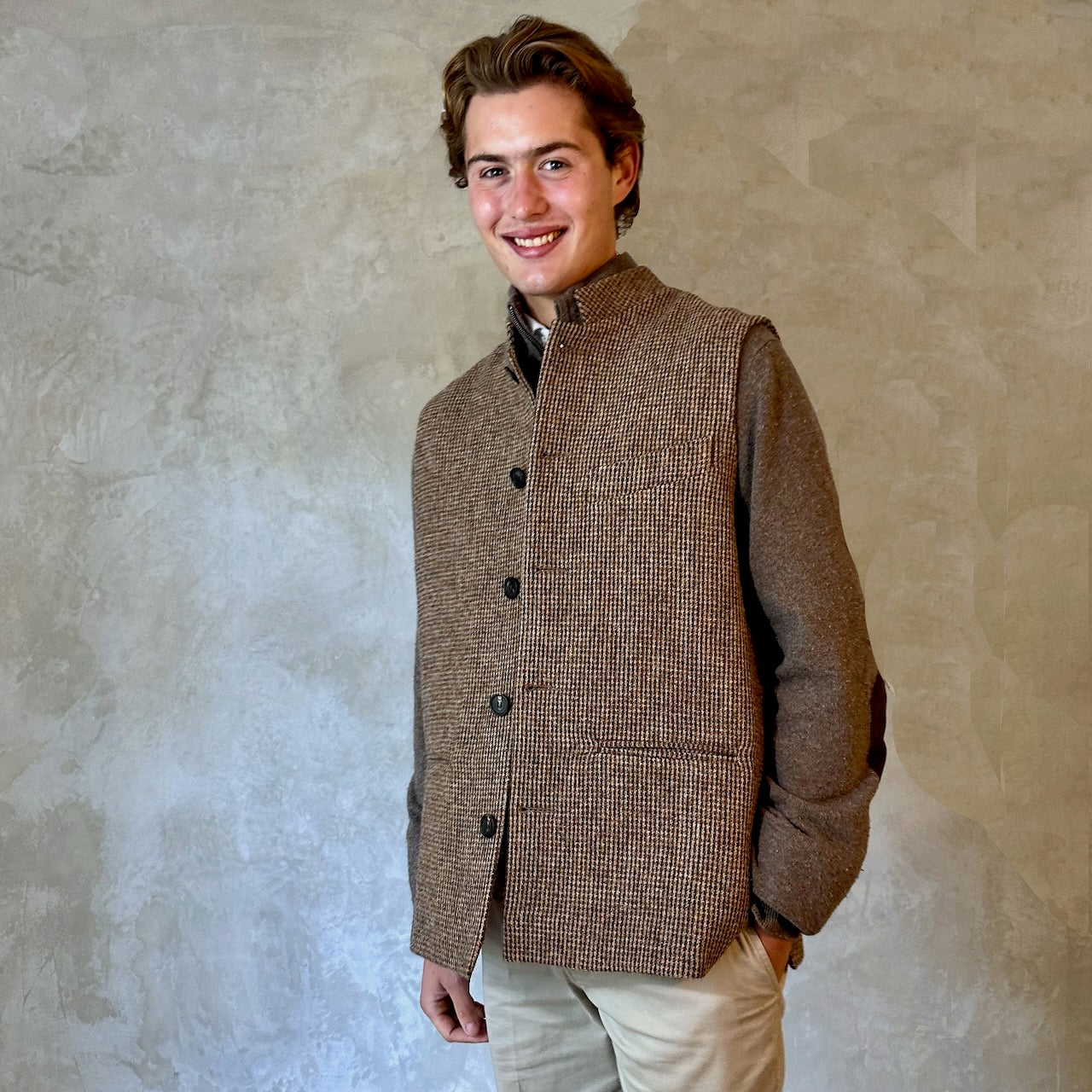 A wonderfully warm Nehru-style gilet in a thick tweed from Hawick. Designed in Wales, oven in England, handmade in London with buttons from Gloucestershire, this is a truly British Waistcoat. Detail Shot. Side vents for ease and five pockets for storage!