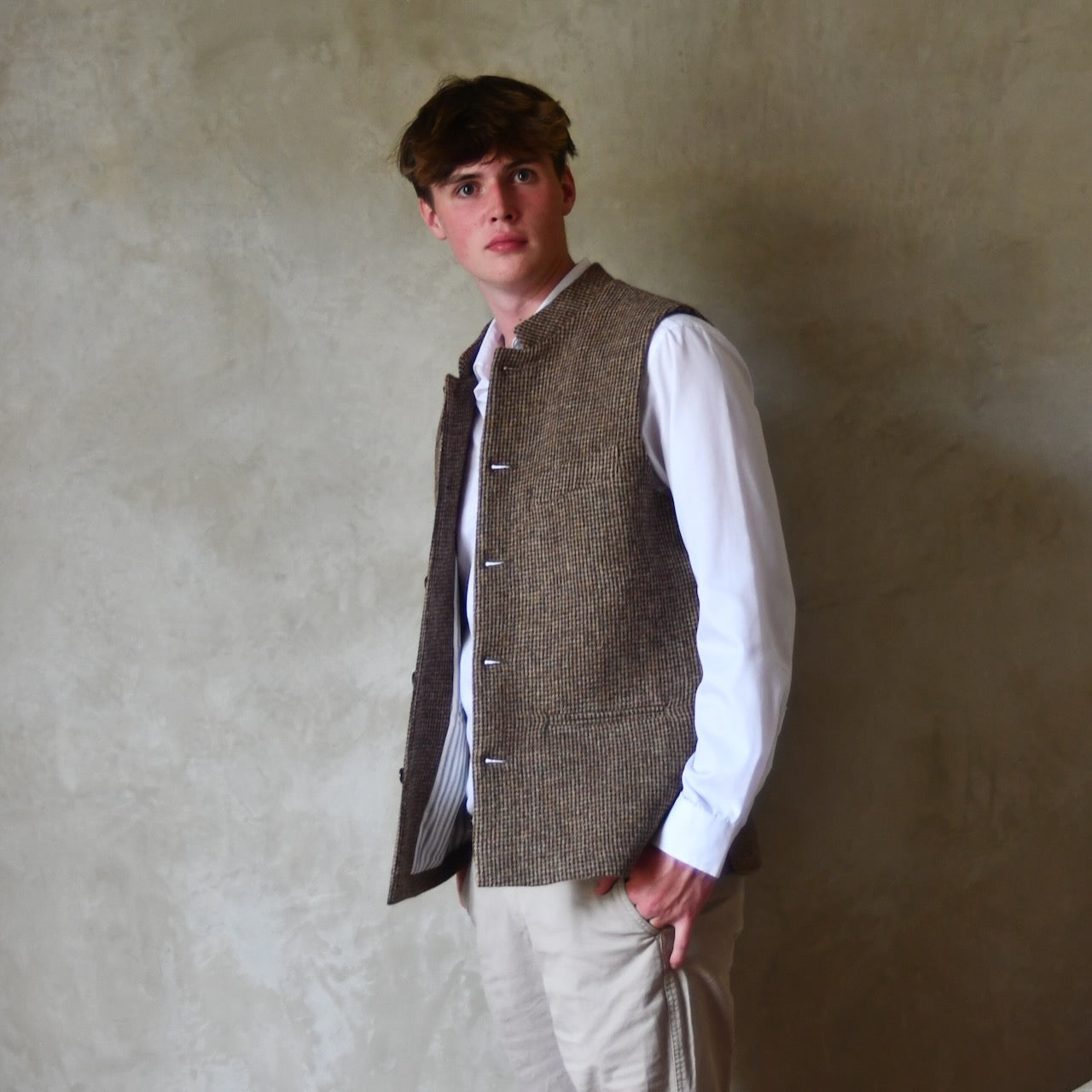 Unbuttoned View of Bespoke Nehru Style Gilet in Brown Patterned Pure Wool Tweed. This tweed from Lovat Mill has a delicate patterning. Shown over a white shirt with Chinos.