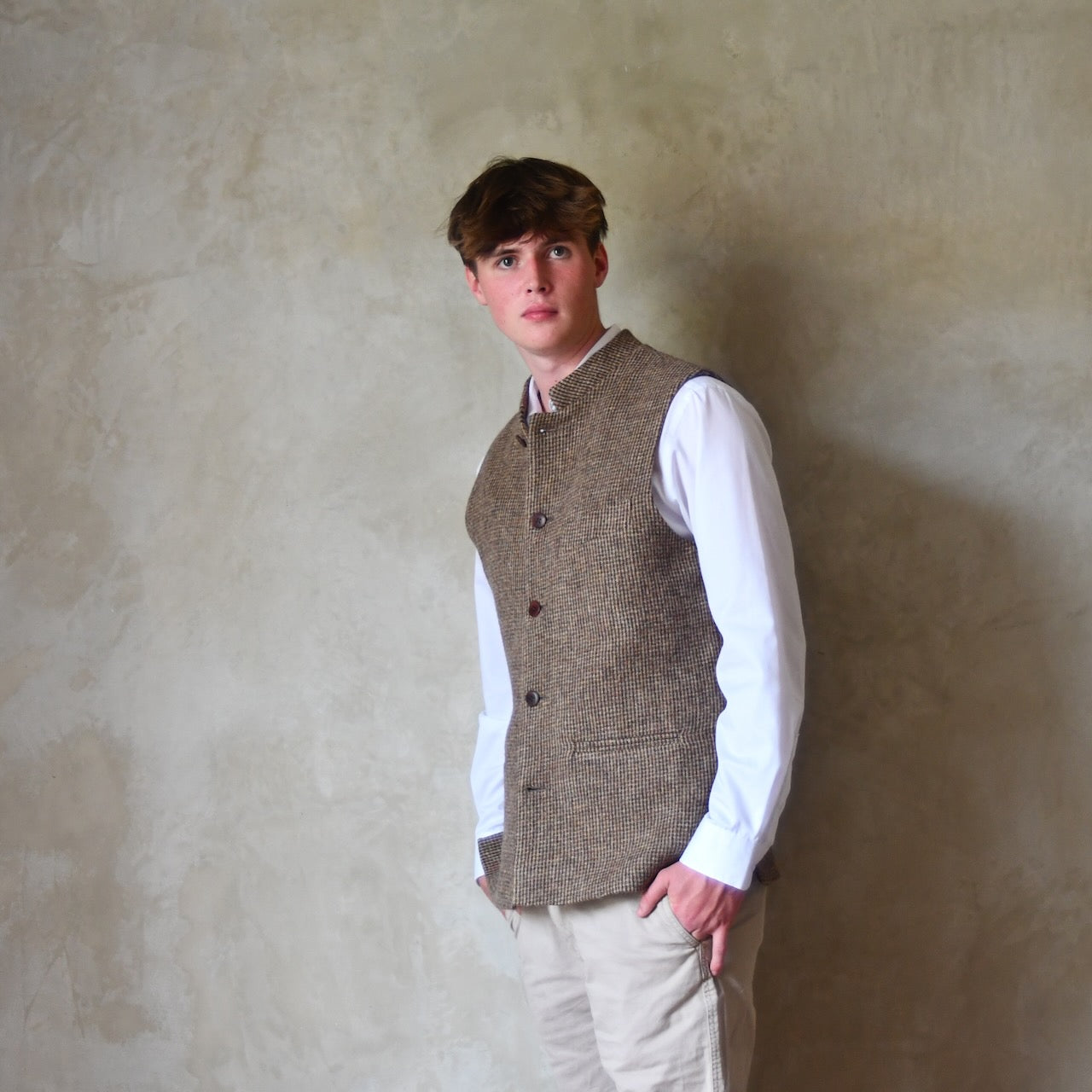 Buttoned Side View of Bespoke Nehru Style Gilet in Brown Patterned Pure Wool Tweed. This tweed from Lovat Mill has a delicate patterning. Shown over a white shirt with Chinos.