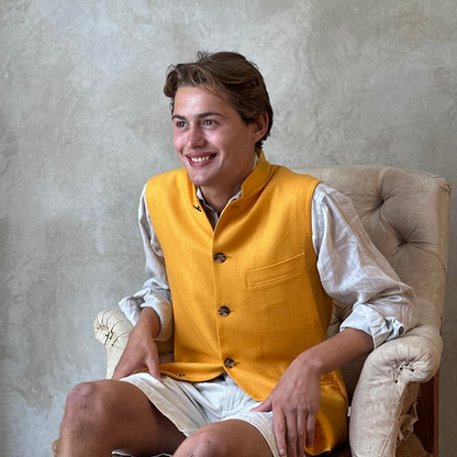 Seated view of summer weight slim-fit gilet in bright yellow silk weave. Handmade in London this tailored cut waistcoat has a Mandarin Collar, Striped Cotton Ticking Lining and five buttons to the front. Made in Great Britain. 