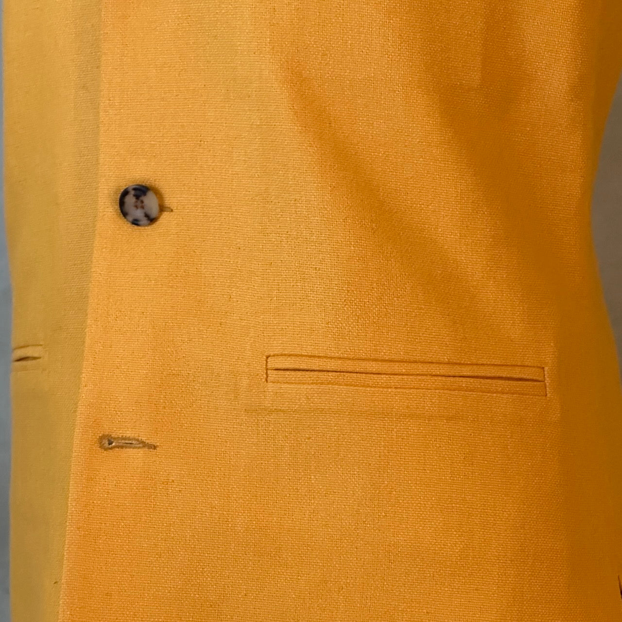 Close up on fabric of summer weight slim-fit gilet in bright yellow silk weave. Handmade in London this tailored cut waistcoat has a Mandarin Collar, Striped Cotton Ticking Lining and five buttons to the front. Made in Great Britain. 
