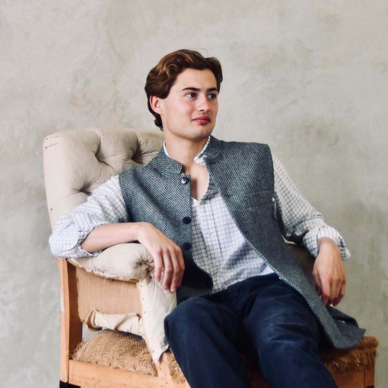 A magical limited edition mid-weight Tailored Cut waistcoat in light grey and blue tiger eye tweed. This tightly woven Yorkshire tweed has an usual patterning giving the overall effect of a mid blue from a distance, it lightens and brightens up on closer inspection as the depths and vivid colours of its patterning are revealed.
Nehru Collar, Striped Ticking lining and a Flat Horn button.
Entirely made in Great Britain. Seated View.