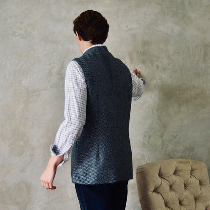 A magical limited edition mid-weight Tailored Cut waistcoat in light grey and blue tiger eye tweed. This tightly woven Yorkshire tweed has an usual patterning giving the overall effect of a mid blue from a distance, it lightens and brightens up on closer inspection as the depths and vivid colours of its patterning are revealed.
Nehru Collar, Striped Ticking lining and a Flat Horn button.
Entirely made in Great Britain. Rear View.